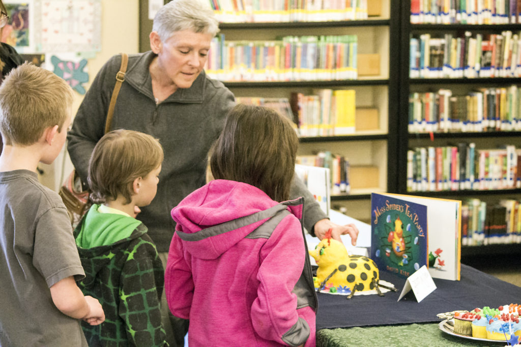 Gina Harder won in two major categories during the second annual Bowman Regional Public Library’s Edible Book Fest. Harder explains to some local children how she made her creation. (Pioneer Photo by Bryce Martin)