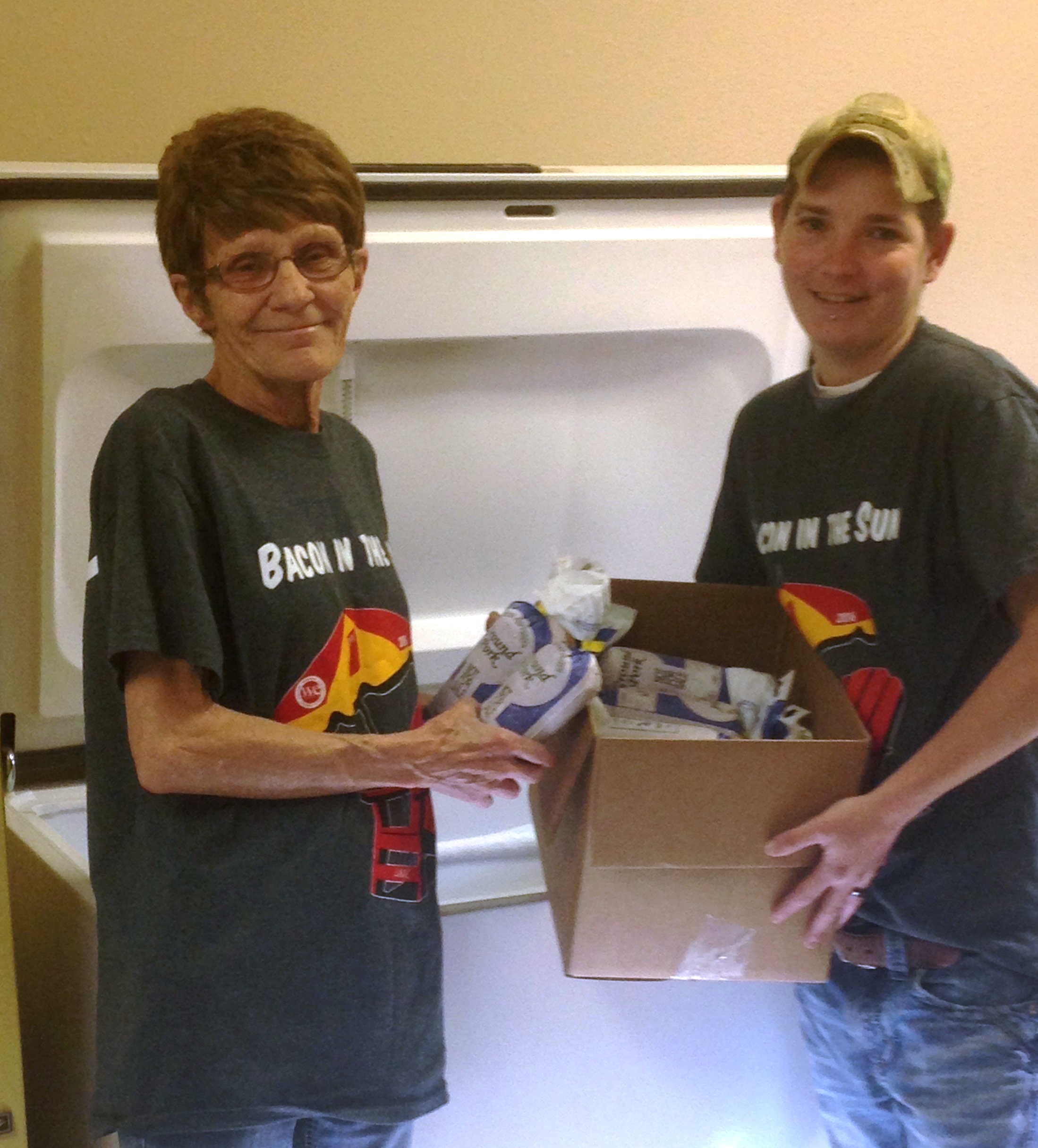 NorDak, LLP, employees Linda Jorgens and Janel Anderson helps fill the Bowman Community Cupboard with 107 pounds of ground pork.